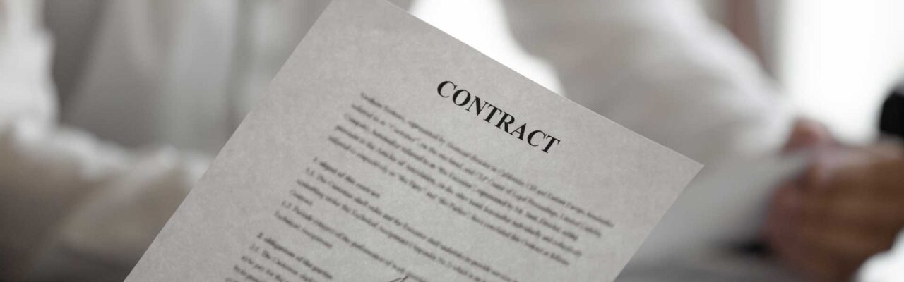 Person holding a piece of paper that says Contract on the top